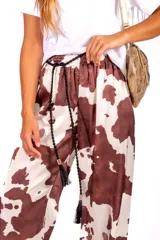 Pantalón con estampado de vaca en satén liviano de caída suave, cintura elastizada y cordón decorativo.