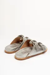 Sandalias marrones de cuero vacuno con doble tira y hebillas metálicas ajustables.
