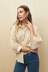 Camisa color beige con bordados florales, cuello clásico, cierre con botones y mangas 3/4 abullonadas.