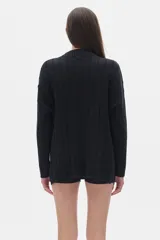 Buzo tejido color crema con cuello alto tipo polera, corte oversized y aberturas laterales.