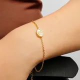 Pulsera dorada con cadena fina y dije circular con el signo zodiacal Virgo en color blanco.