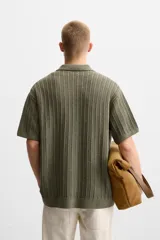 Camisa verde militar de punto con estructura abierta, corte regular fit, cuello solapa, manga corta y cierre frontal con botones.