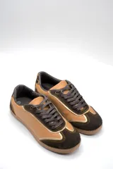 Zapatillas urbanas de cuero color beige con puntera y cordones marrones. Presentan un panel de animal print en el talón y suela de goma color caramelo.