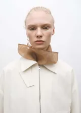 Chaqueta color crema con cierre frontal con cremallera, cuello camisero, manga larga y diseño oversize.