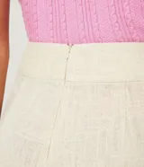 Short color beige confeccionado en viscolino con detalle de pliegues diagonales y cierre de cremallera.