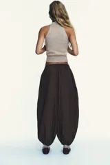 Pantalón bombacho marrón de nylon con cintura elástica, bolsillos laterales ocultos y bajo abullonado con elástico.