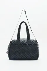 Bolso marrón con diseño matelassé, doble asa corta, correa larga desmontable y dos bolsillos frontales. Incluye llavero de corazón y dijes desmontables.