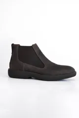 Bota Chelsea color marrón oscuro, confeccionada en cuero, con elásticos laterales y suela de goma.