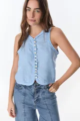 Top sin mangas color beige, con escote en V y cierre frontal de botones de nácar. Presenta costuras decorativas en el borde del escote y sisas.