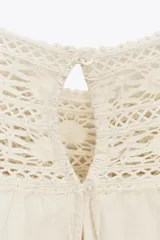 Vestido corto color crudo confeccionado en hilatura con mezcla de algodón y lino. Presenta cuello redondo, manga corta abullonada, detalle de bordados a tono y bajo recto. Cierre en espalda con abertura y botón.