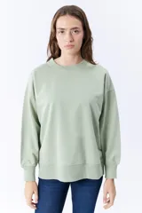 Buzo deportivo verde liso de corte holgado, con cuello redondo y mangas largas.