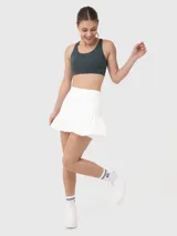 Falda deportiva blanca tipo skort, con short interno y falda plisada con volados.