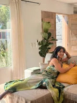 Vestido largo de tela fluida, color verde esmeralda con estampado abstracto en tonos turquesa y detalles dorados. Diseño asimétrico con un solo tirante tejido en el hombro.