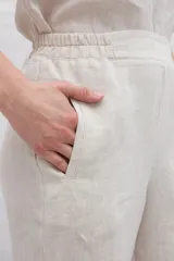 Pantalón de lino color marrón, de corte recto y tiro alto, con cintura elástica y bolsillos laterales.