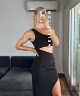 Vestido midi negro con corte asimétrico, una manga, abertura lateral y frunce en la cintura.