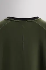Camiseta deportiva verde militar confeccionada en tejido estructurado, ligero y elástico. Tiene cuello redondo, manga corta y bajo con aberturas laterales. Incluye logo estampado en el bajo.