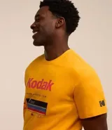 Remera amarilla de algodón con cuello redondo y mangas cortas. Estampado frontal con el logo de Kodak y un rollo de película.