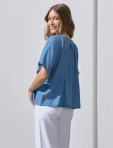 Blusa celeste de lyocell con escote en V, punto smock y lazo de ajuste.