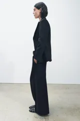 Blazer negro con cuello solapa de muescas y manga larga. Tiene falsos bolsillos de vivo en el delantero, forro interior a tono y cierre frontal cruzado con botón a presión.