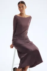 Pollera midi color marrón con leve brillo y caída suave. Modelo de tiro alto con elástico oculto en la cintura y leve vuelo en el bajo.