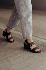 Sandalias negras de cuero con estampado de leopardo, tiras anchas y hebilla metálica.