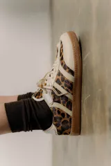 Zapatillas urbanas de cuero beige con estampado animal print, detalles en blanco y suela de goma caramelo y tostado.