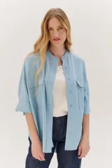Sobrecamisa celeste de corte recto, con cuello mao, mangas 3/4 con puños y cierre frontal con botones. Tiene dos bolsillos de parche en el pecho.