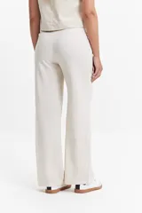 Pantalón de vestir color crema, de tiro medio, corte recto y pierna ancha.