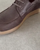 Zapato náutico de cuero vacuno color marrón con cordones y suela clara.