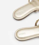 Sandalia plana tipo mule con tiras acolchadas en tonos dorado y plateado alternados, puntera cuadrada y suela plana.