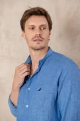 Camisa celeste de lino con cuello mao, corte slim fit, manga larga con puños abotonados y cierre frontal con botones.