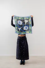 Pañuelo cuadrado de seda con estampado de flores y limones sobre fondo negro, con borde azul y blanco.