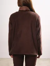Campera marrón con frente capitoneado y mangas de sherpa. Tiene cuello alto, cierre frontal y bolsillos laterales.