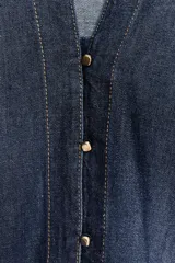 Camisa de denim azul con cuello de solapa, escote en pico, cierre frontal con botones y mangas anchas hasta el codo.