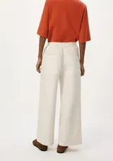 Pantalón de lino color crema, de corte recto y tiro alto, con cintura elástica ajustable con cordón y bolsillos laterales.