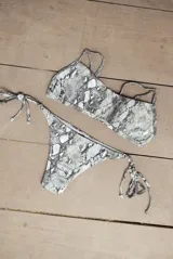Conjunto de bikini con estampado de piel de serpiente en tonos grises. El corpiño es bandeau con breteles regulables y la bombacha es vedetina con tiras a los costados para atar.