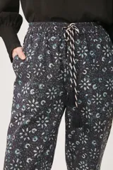 Pantalón babucha negro con estampado floral en tonos celeste y blanco.