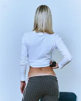 Pantalón gris con finas rayas verticales blancas, corte bootcut y cintura baja con puntilla blanca.