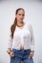 Blusa blanca de encaje con cuello en V, volados en el frente y mangas largas.