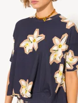 Remera azul marino con estampado de flores blancas y amarillas, de corte holgado, cuello redondo y mangas cortas.