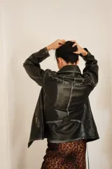 Chaqueta tipo biker de cuero sintético negro con efecto desgastado y detalles de tachas plateadas en solapas y hombros.