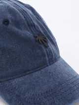 Gorro de béisbol azul denim con logo de palmera bordado en negro.