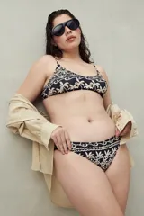 Bikini de dos piezas con estampado tropical en tonos beige y negro. El corpiño es de corte triangular con tirantes finos y la bombacha es de tiro medio.