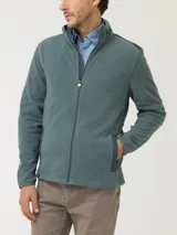 Campera polar celeste de poliéster reciclado con aplicaciones de tela canvas de algodón en los hombros, dos bolsillos frontales con cierre, bolsillos internos, cuello alto y cierre completo.