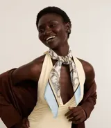 Pañuelo rectangular de satén con estampado paisley en tonos blanco, azul claro y beige. El pañuelo se anuda bajo la barbilla, cubriendo la cabeza.