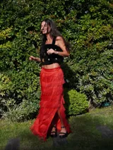 Falda larga color verde oliva con múltiples capas de flecos largos, creando un efecto texturizado. La falda tiene un tajo lateral.