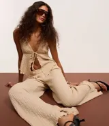 Pantalón largo color beige, de poliéster texturizado, con cintura elástica y bolsillos laterales.