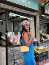 Bandolera pequeña color beige, de material símil cuero, con correa fina y logo grabado en el frente.