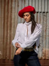 Blusa blanca de algodón con cuello alto con volados, mangas largas abullonadas y bordado calado.