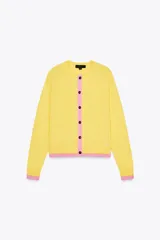 Chaqueta de punto amarilla con cuello redondo, manga larga y cierre frontal con botones negros. Presenta ribetes rosas en cuello, puños y bajo.